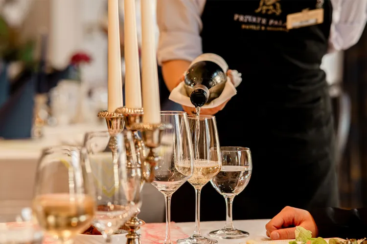 A waiter pours champagne into glasses at a festively laid banquet table in the restaurant of the Rugard Thermal Strandhotel.