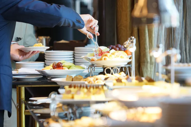 A guest helps himself to the generous breakfast buffet with fruit and pastries.