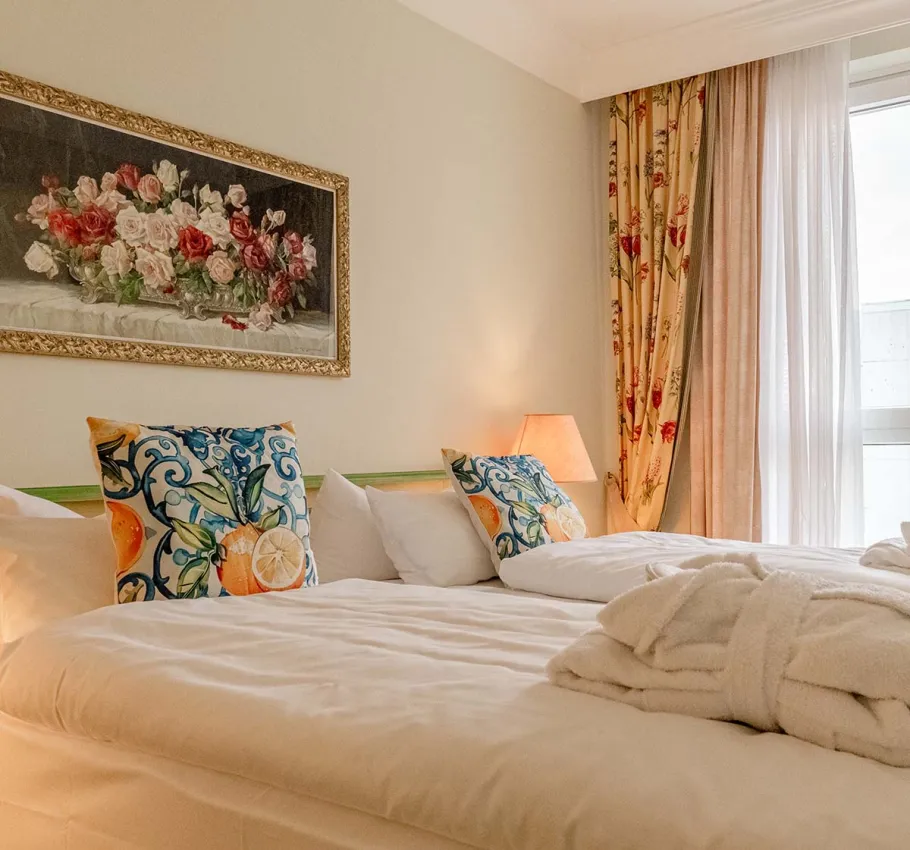 Doppelzimmer im Rugard Strandhotel mit großem Doppelbett, zwei bunten Kissen und Gemälde an der Wand