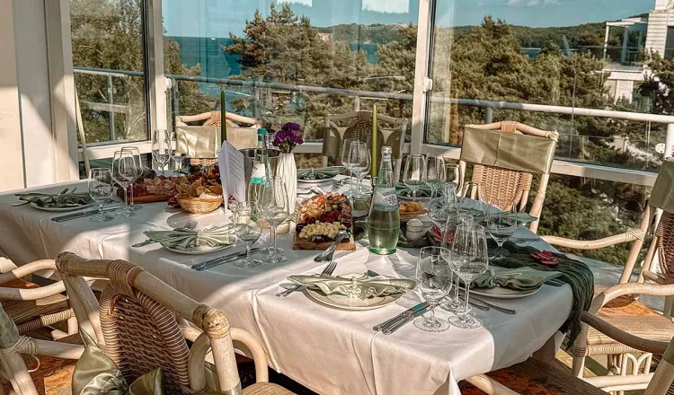 Dekorierter Tisch in einem hellen Restaurantraum in Binz mit Blick auf das Meer und einem Bernsteinwasserfall als Dekoration.