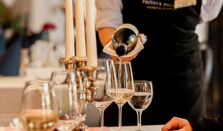 Ein Kellner schenkt Champagner in Gläser bei festlich gedecktem Tisch eines Banketts im Restaurant des Rugard Thermal Strandhotels ein.
