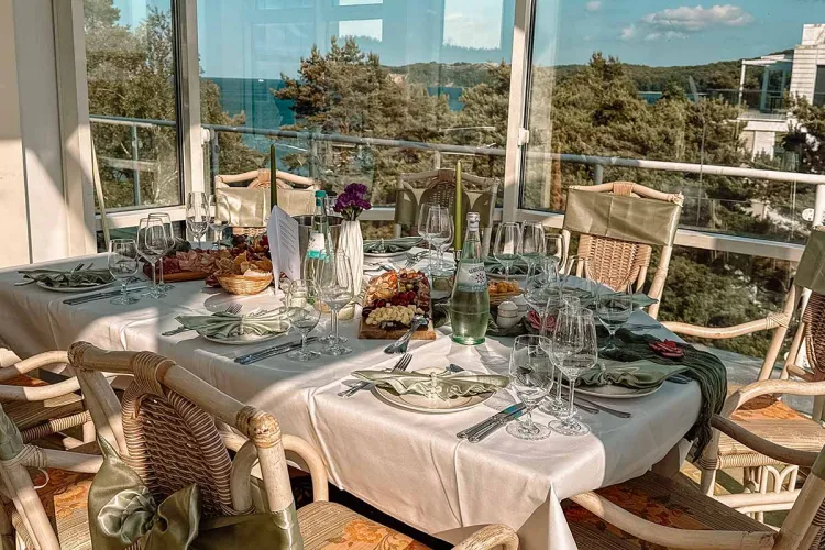 Decorated table in a bright restaurant room overlooking the sea and decorated with an amber waterfall.