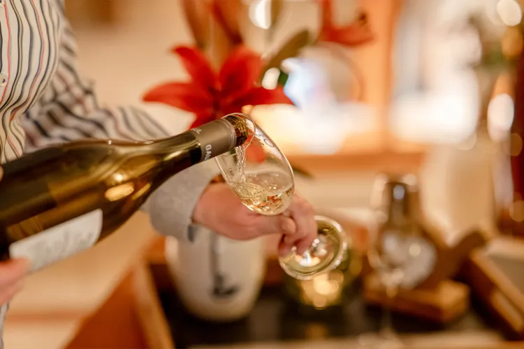 Champagne is poured into a glass, festive decorations in the background at a banquet in the Rugard Thermal Strandhotel.
