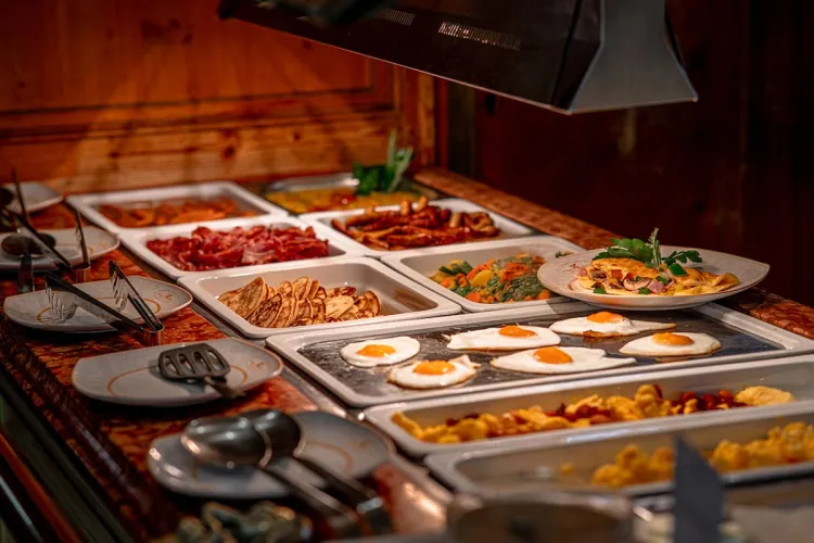 A varied and fresh breakfast buffet including fried eggs, pancakes and bacon.