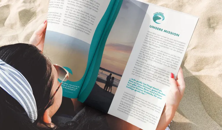 Frau mit Magazin am Strand von Binz – Rugard Thermal Strandhotel beteiligt sich aktiv an der Umweltkampagne „Ohne Meer wird schwer“