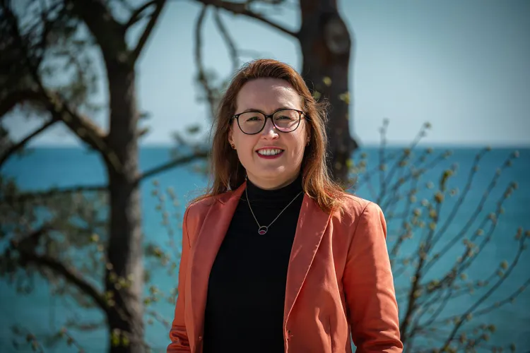 Dorothee Schicht on the beach in Binz with water and trees behind – Executive assistant at Rugard Thermal Strandhotel