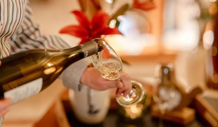 Champagner wird in ein Glas eingeschenkt, im Hintergrund festliche Deko bei einem Bankett im Rugard Thermal Strandhotel.