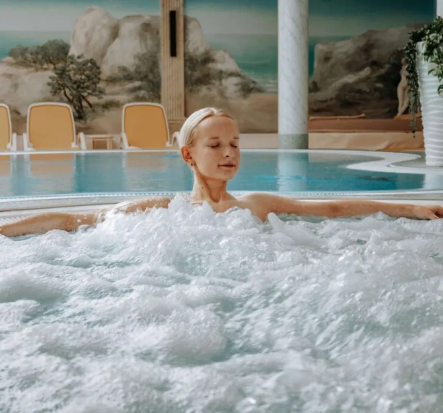Eine Frau entspannt in einem Whirlpool in einem Wellnesshotel bei einem Angebot an der Ostsee.
