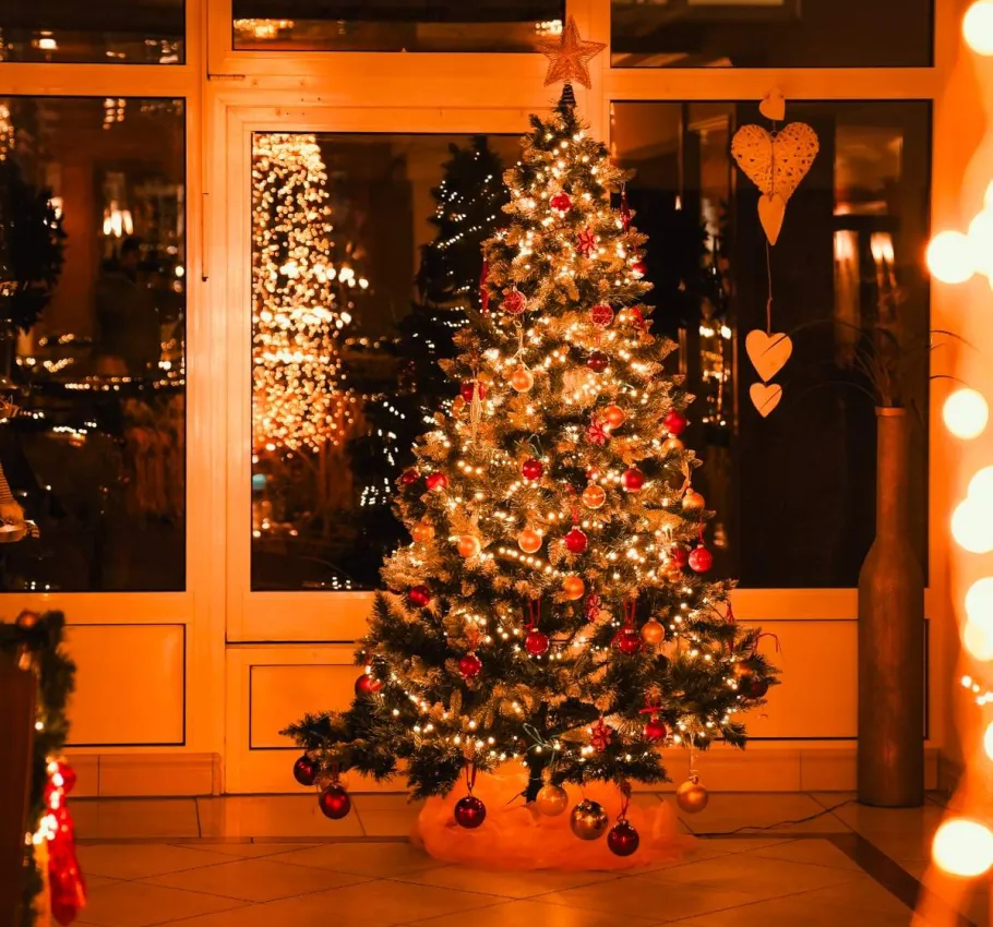 Festlich beleuchteter Weihnachtsbaum in einem gemütlich dekorierten Hotelbereich während der Weihnachtszeit.
