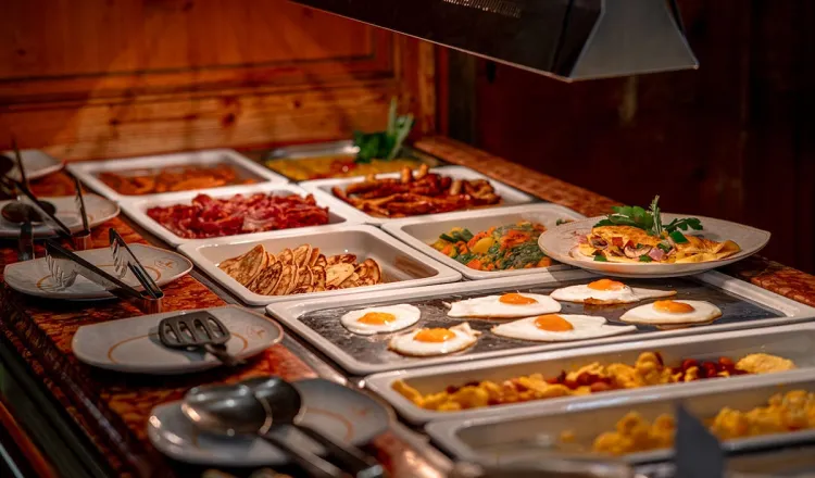 Ein abwechslungsreiches und frisches Frühstücksbuffet mit Spiegeleiern, Pfannkuchen und Speck im Hotelrestaurant in Binz.