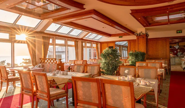 Dekorierte Vierertische in einem sonnendurchfluteten Restaurantraum in Binz mit Blick auf die Ostsee.