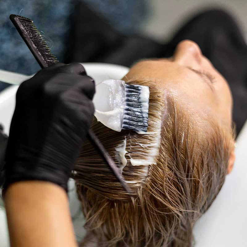 Applying new hair colour to a customer's hair with a brush.