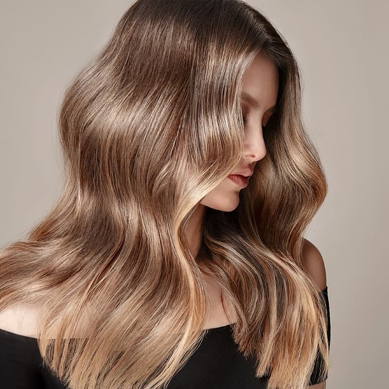 A voluminous wavy hairstyle on the long hair of a blonde woman.
