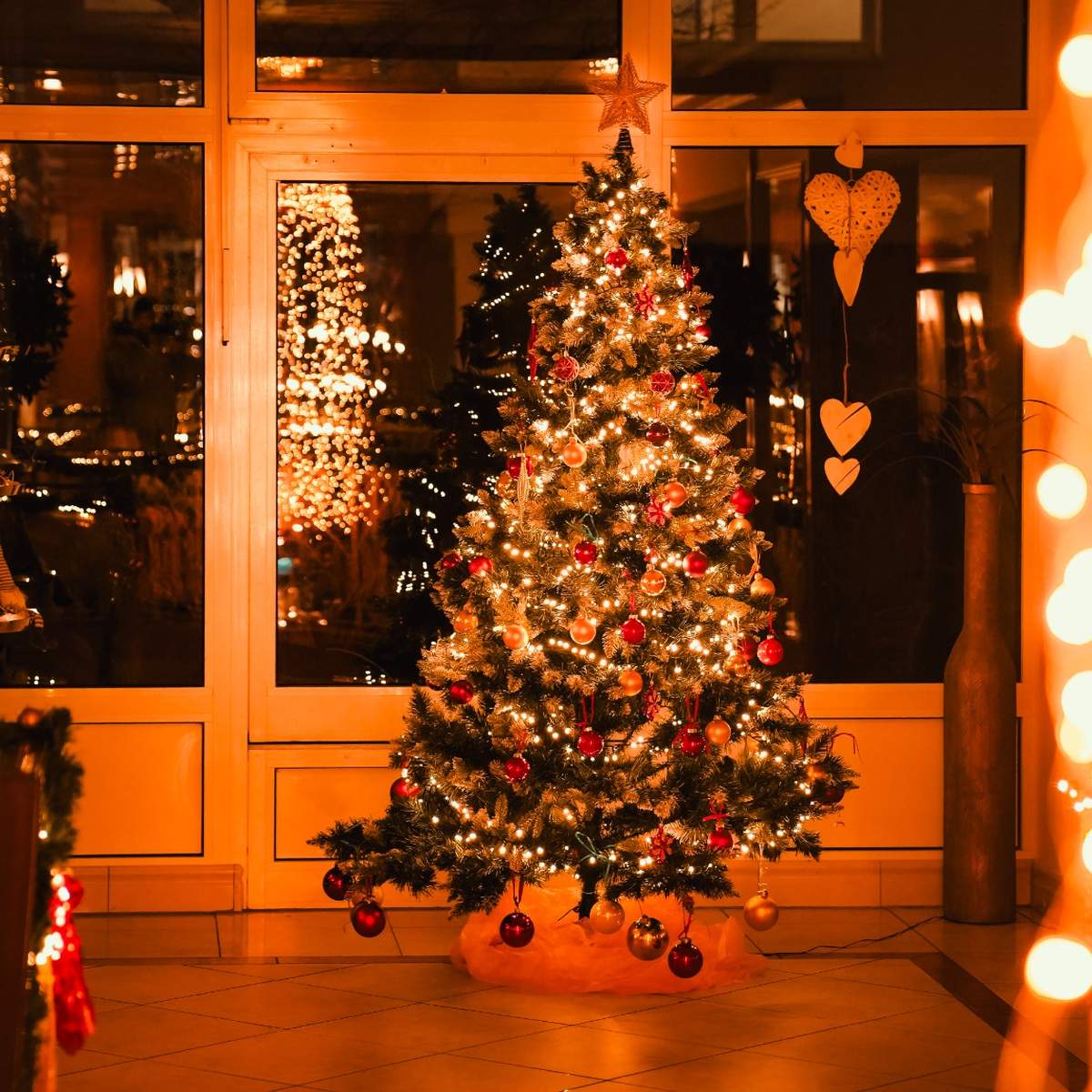 Festlich beleuchteter Weihnachtsbaum in einem gemütlich dekorierten Hotelbereich während der Weihnachtszeit.