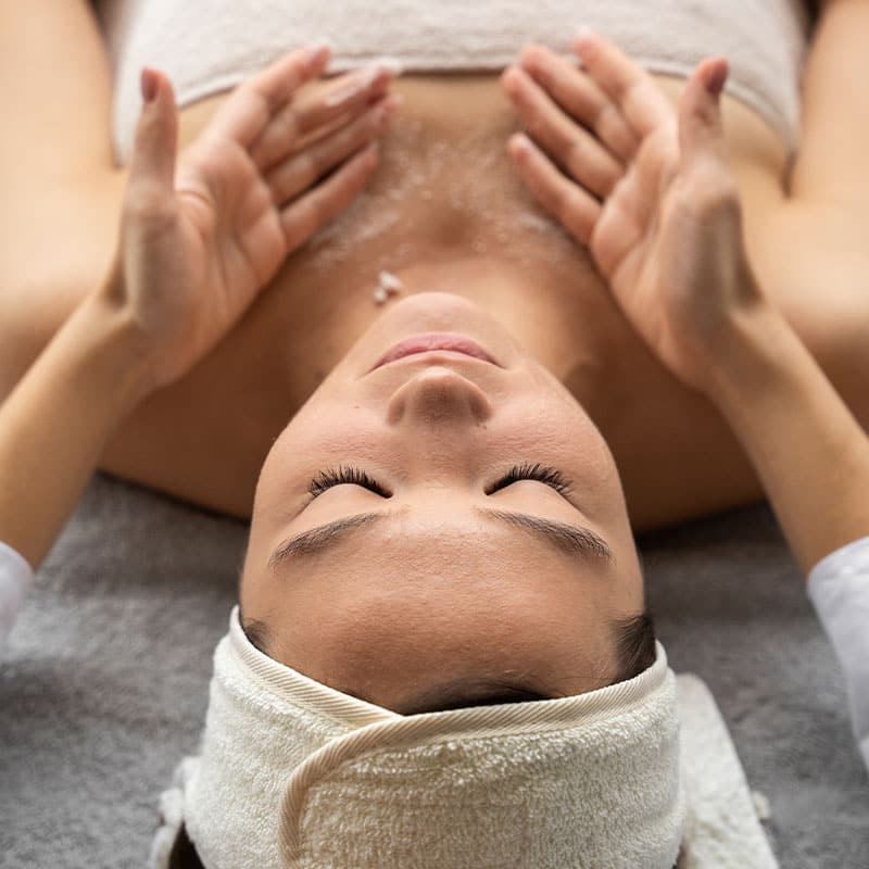 A woman relaxes on a treatment table with a décolleté peeling.