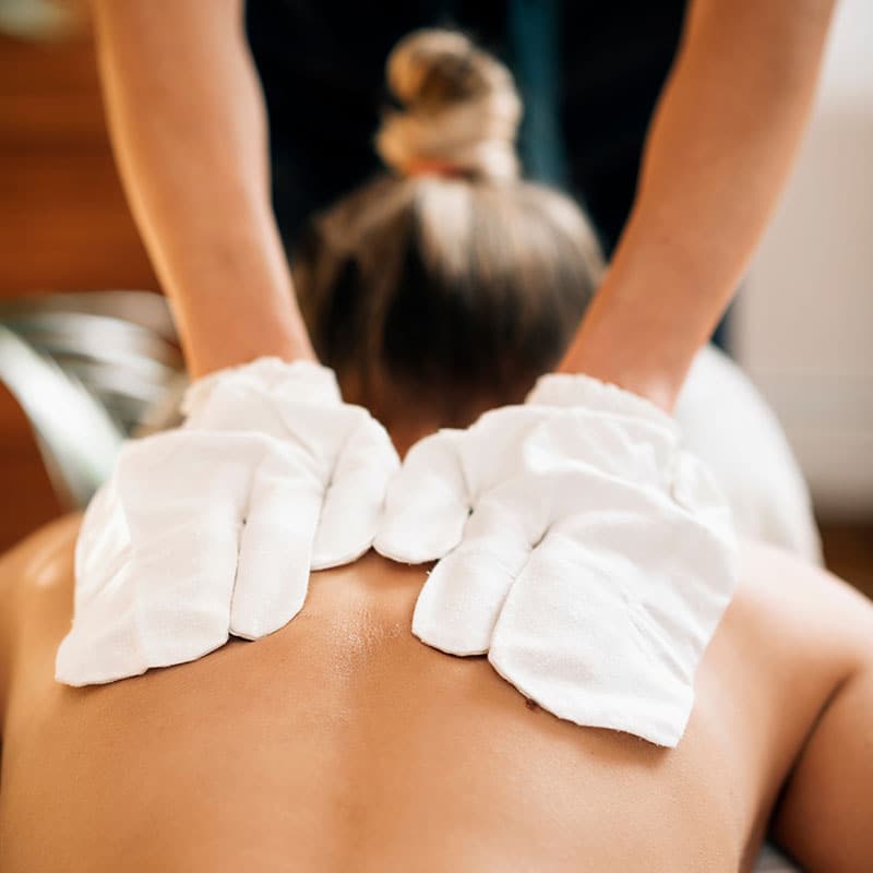 A woman receives a back massage with original Ayurvedic silk gloves.