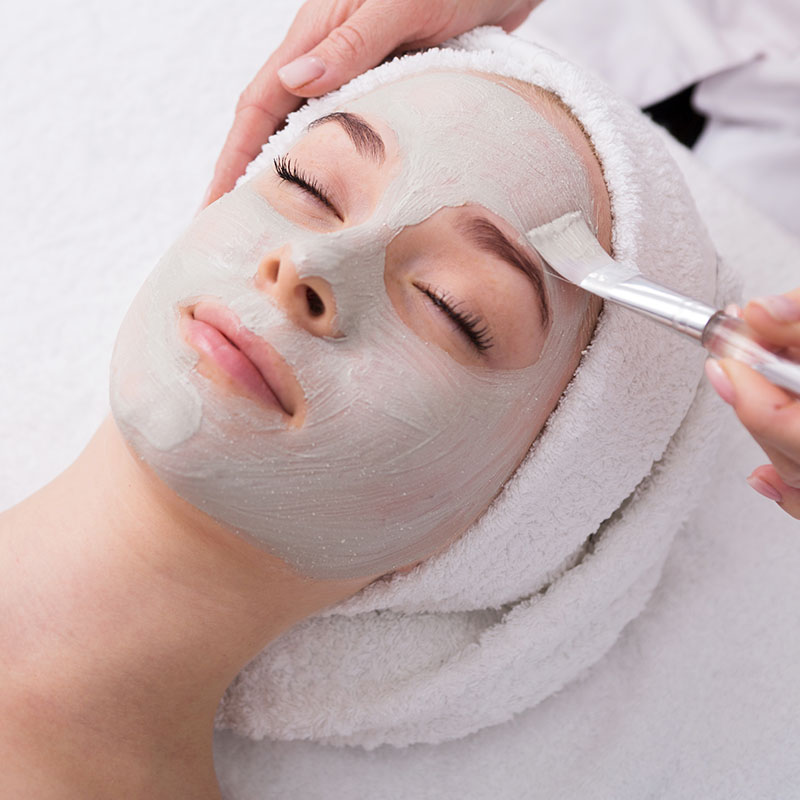 A gray face mask from Biodroga is gently applied to a woman.