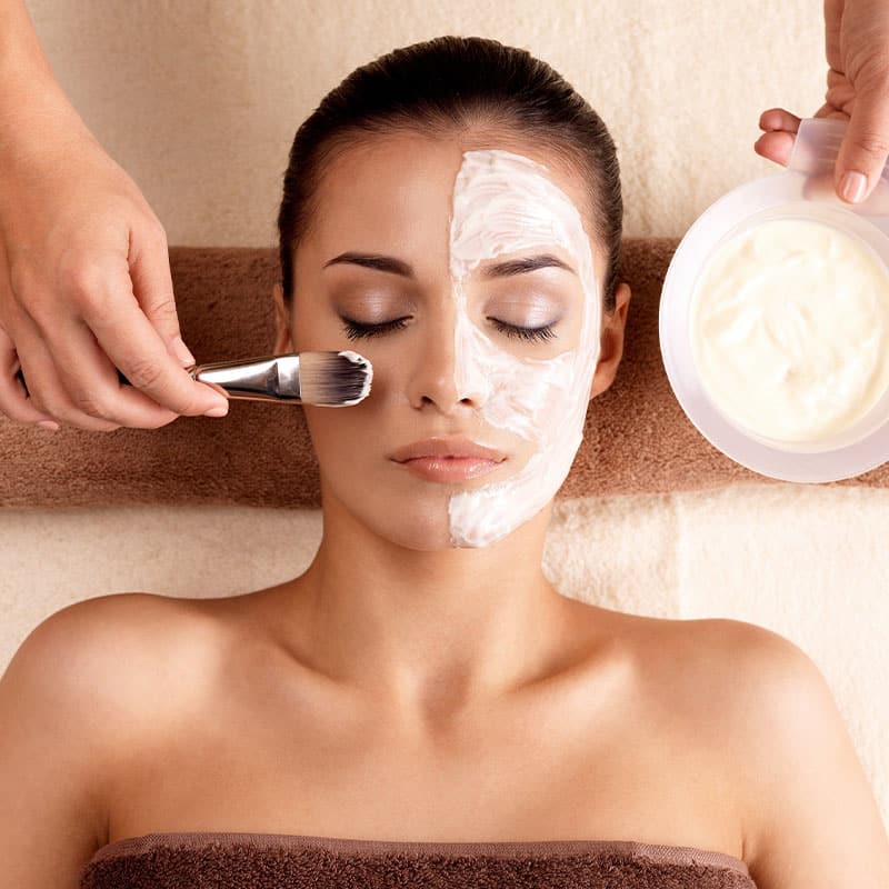 A woman enjoys a rich facial treatment with mask.