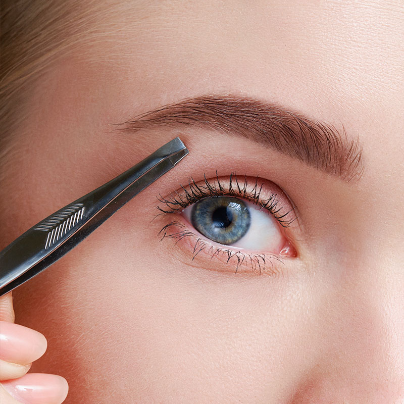 Close-up of an eye tweezer held between the eye and the breast.
