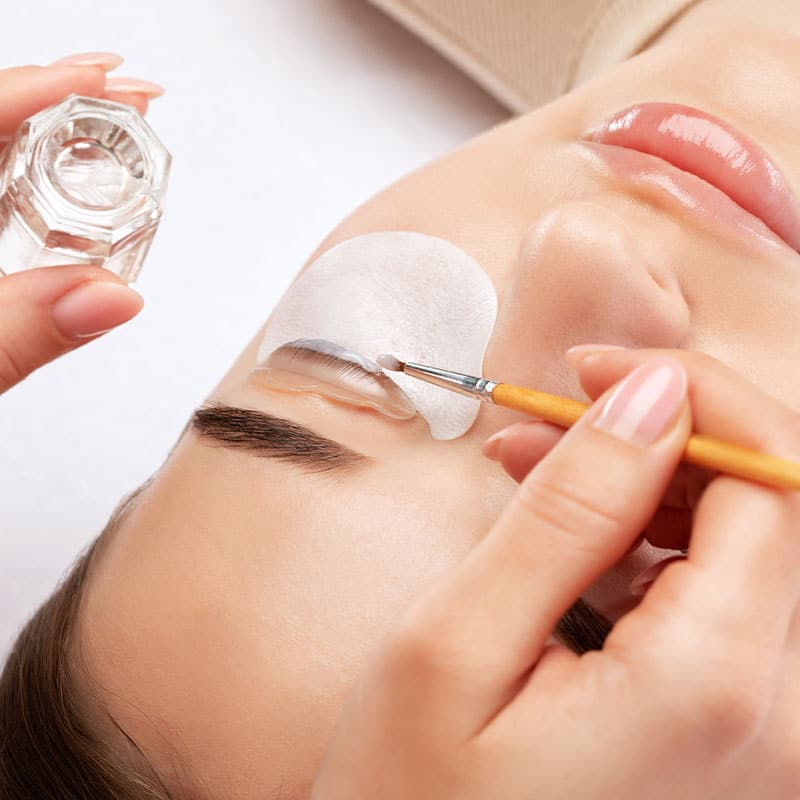 A woman receives an eyelash curler with an adhesive silicone mould and brush.