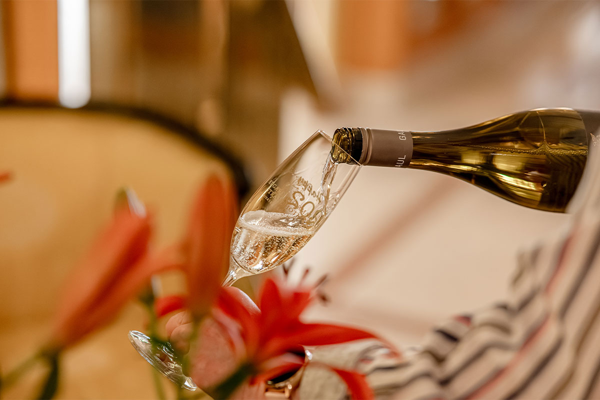 Ein Glas Champagner wird elegant eingeschenkt, festlich gedeckter Tisch beim Bankett im Rugard Thermal Strandhotel.