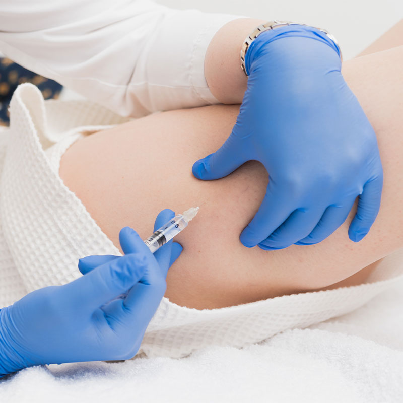 Detailed shot of a medical injection lipolysis with blue gloves from ÄsthetikaMed in the Arkona Strandhotel on Rügen.