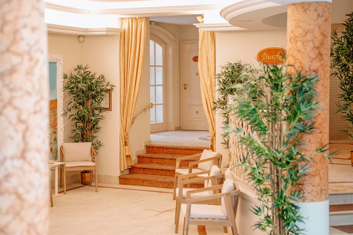 Blick auf Ruhebereich mit Liegen, Blumenarrangements und warmem Licht im Hotel mit Sauna in Binz auf Rügen.