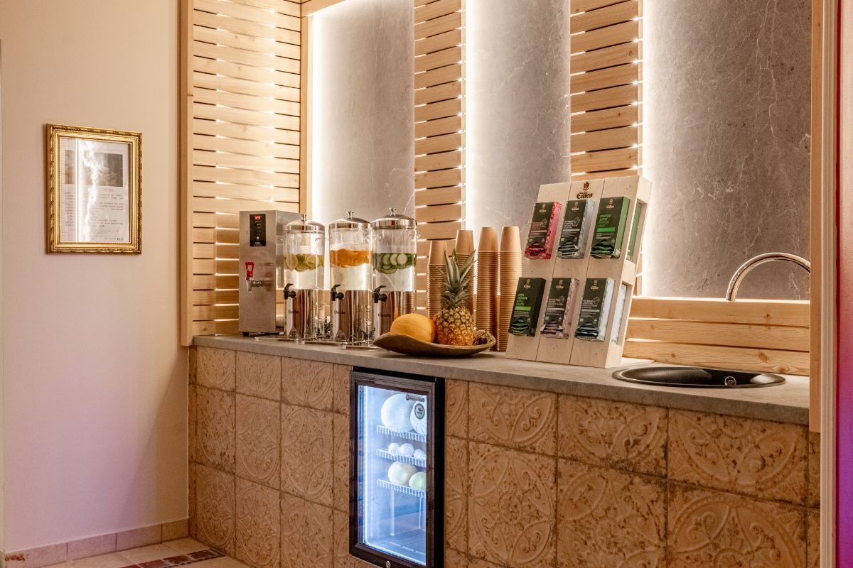 Wasserstation mit Glasdispensern, frischen Früchten und Trinkbechern im Spa-Bereich im Hotel mit Sauna in Binz auf Rügen.